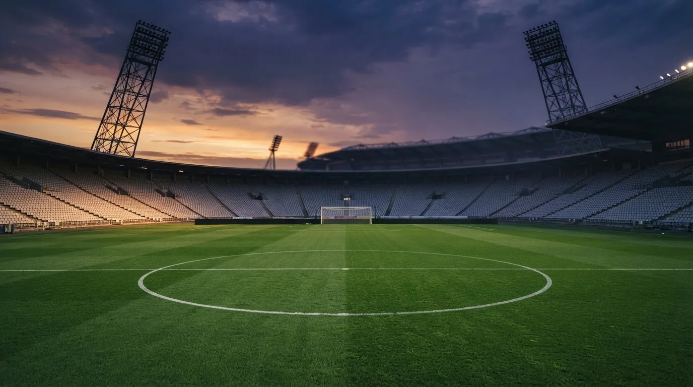 An empty football stadium with floodlight masts at dusk