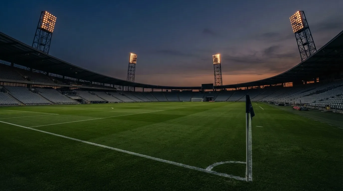 An empty football stadium with floodlight masts at dusk