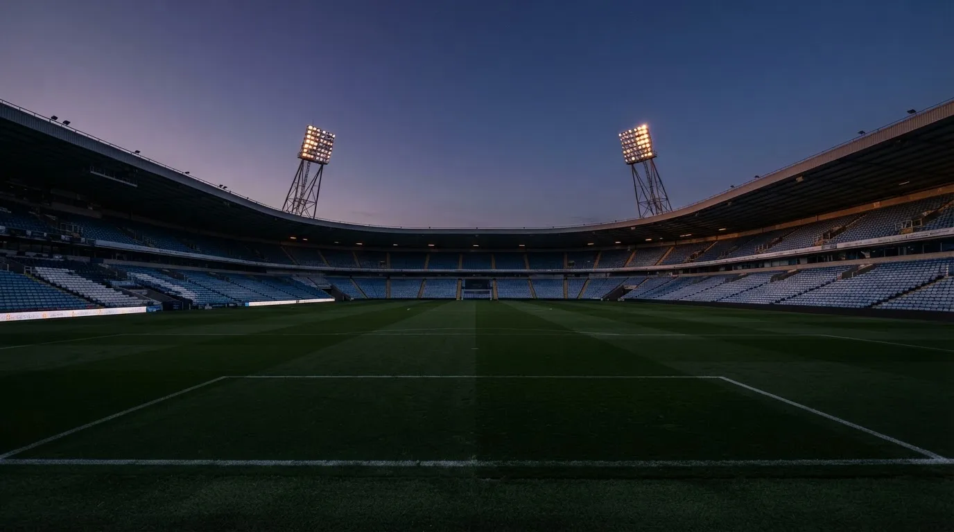 An empty football stadium with floodlight masts at dusk