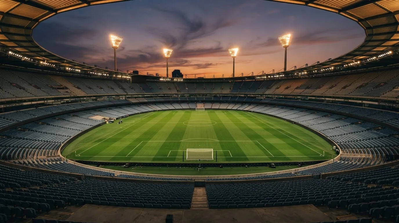 An empty football stadium with floodlight masts at dusk