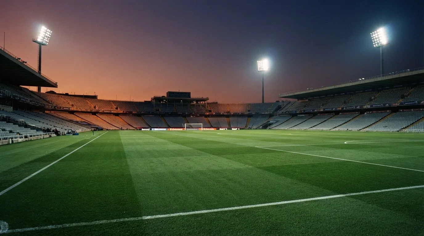 An empty football stadium with floodlight masts at dusk
