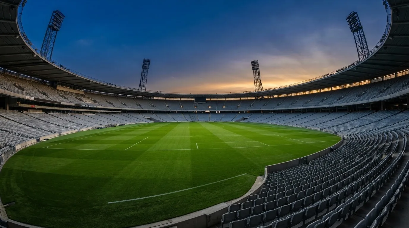An empty football stadium with floodlight masts at dusk