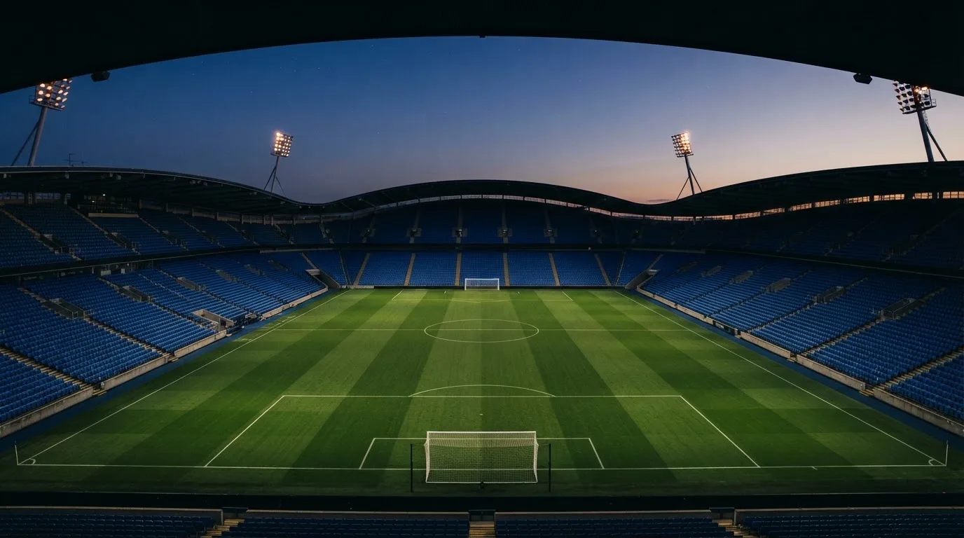 An empty football stadium with floodlight masts at dusk