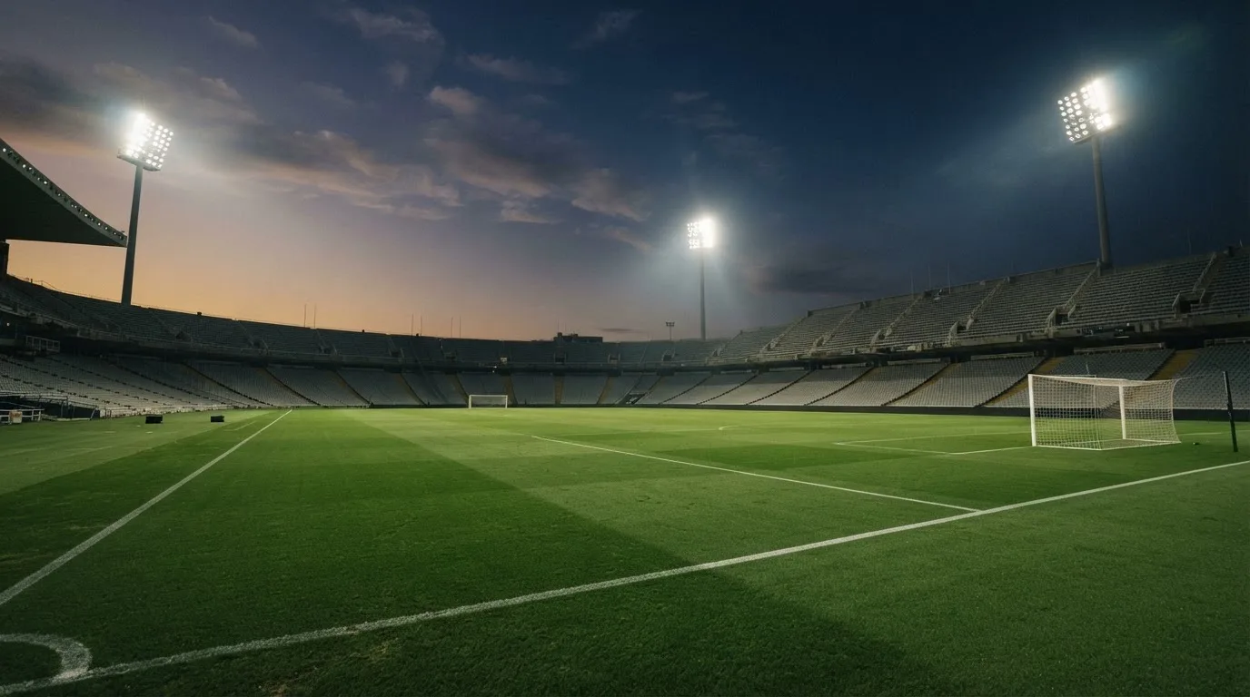 An empty football stadium with floodlight masts at dusk
