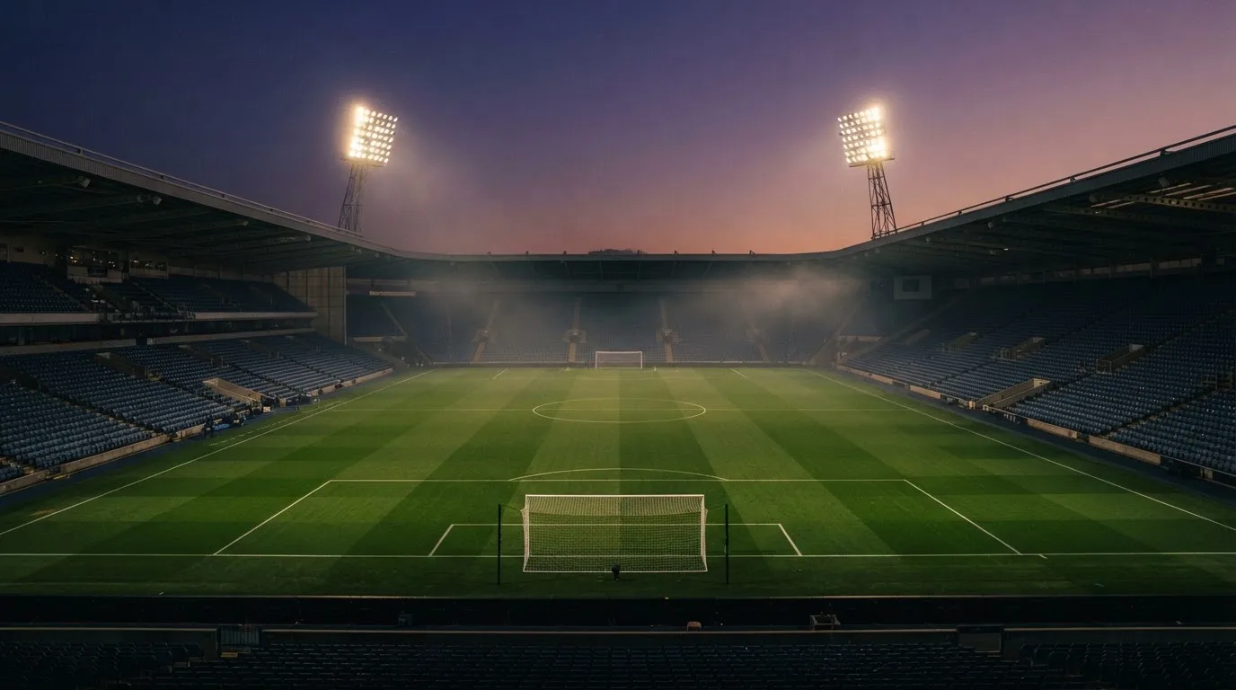 An empty football stadium with floodlight masts at dusk