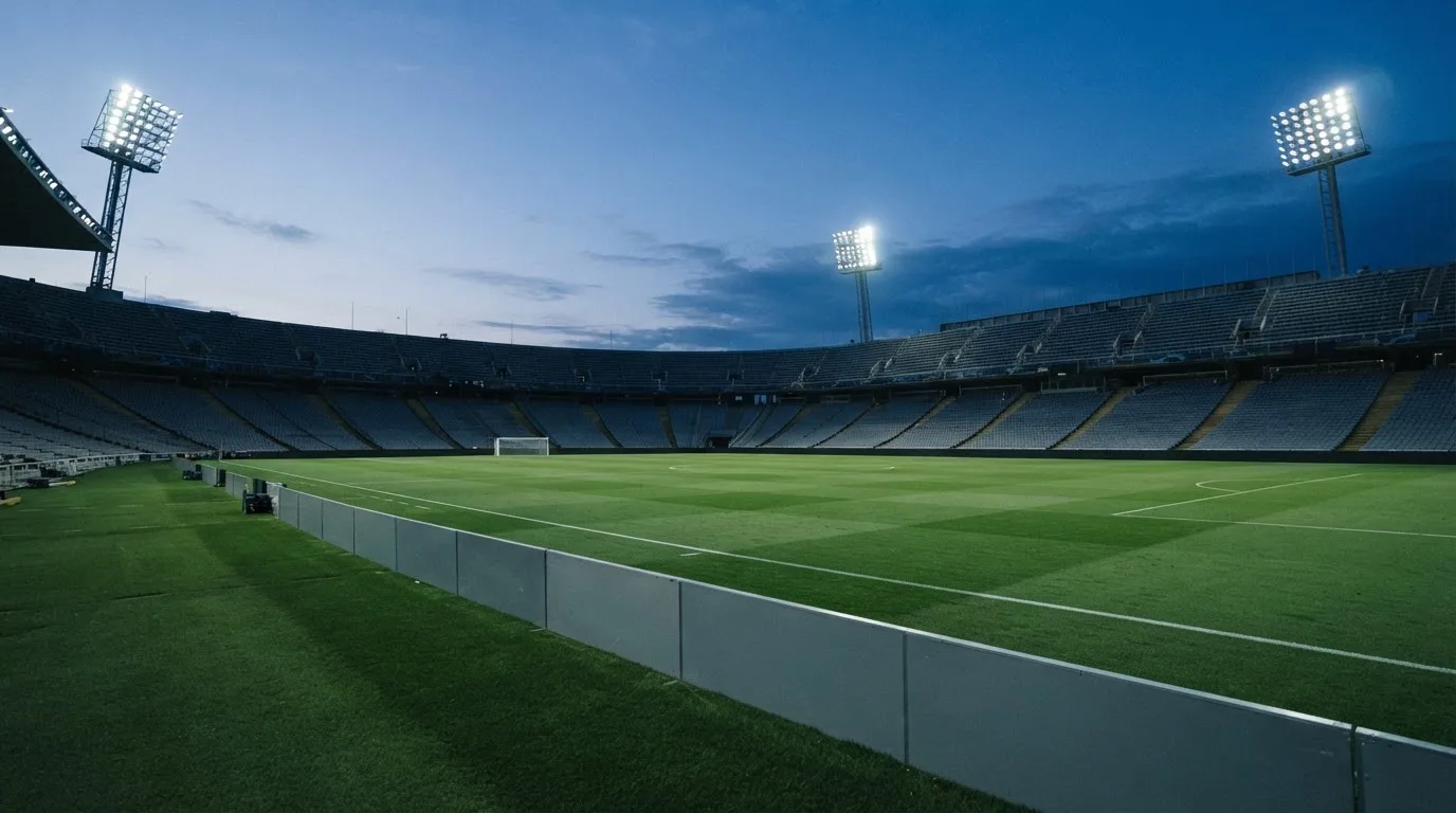 An empty football stadium with floodlight masts at dusk