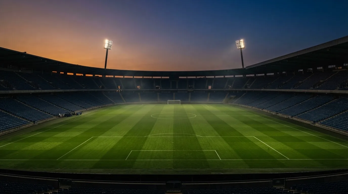 An empty football stadium with floodlight masts at dusk