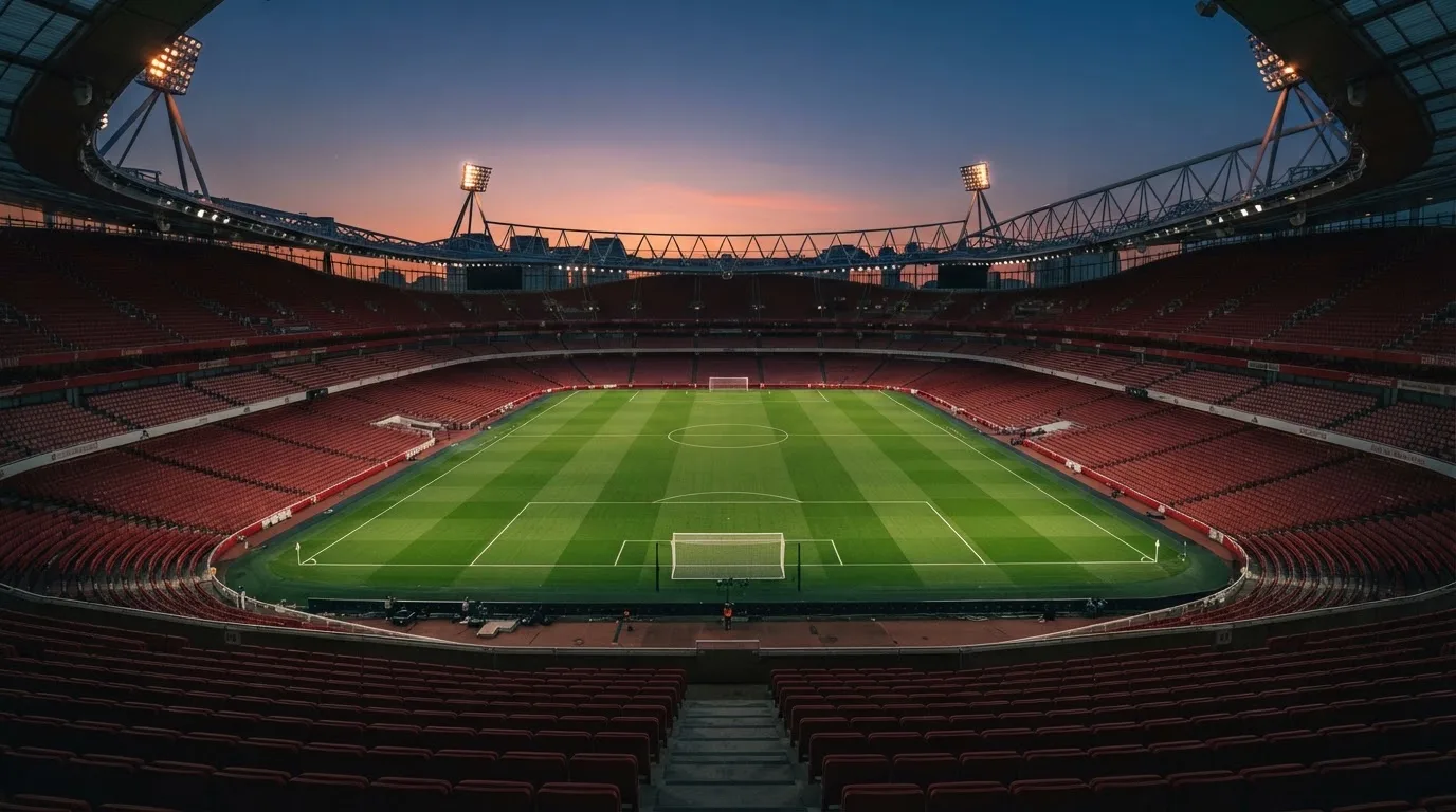 An empty football stadium with floodlight masts at dusk