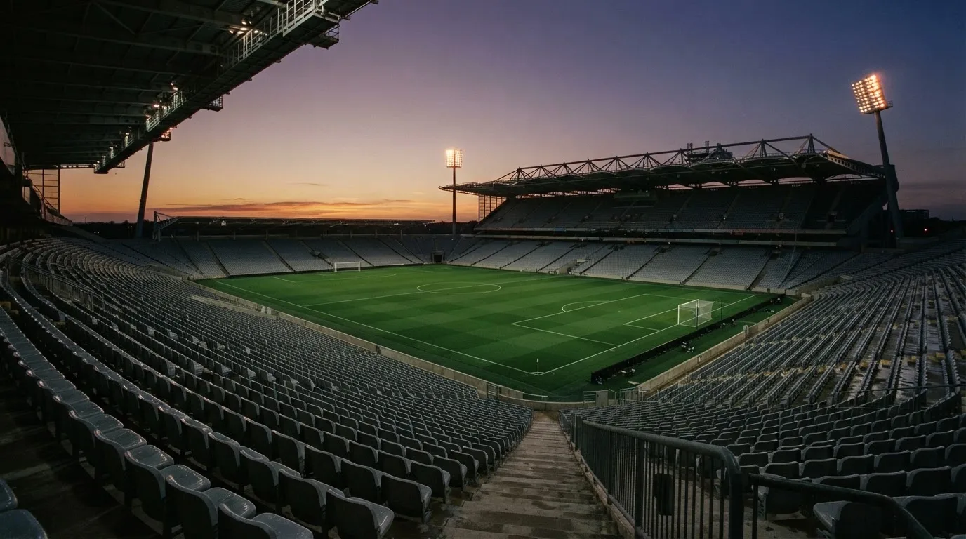 An empty football stadium with floodlight masts at dusk