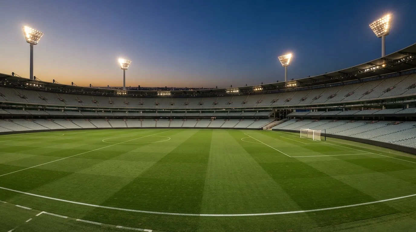 An empty football stadium with floodlight masts at dusk
