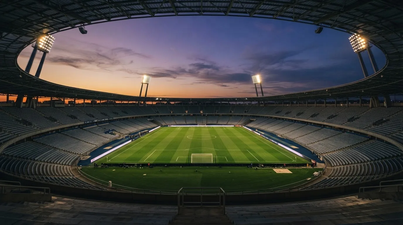 An empty football stadium with floodlight masts at dusk