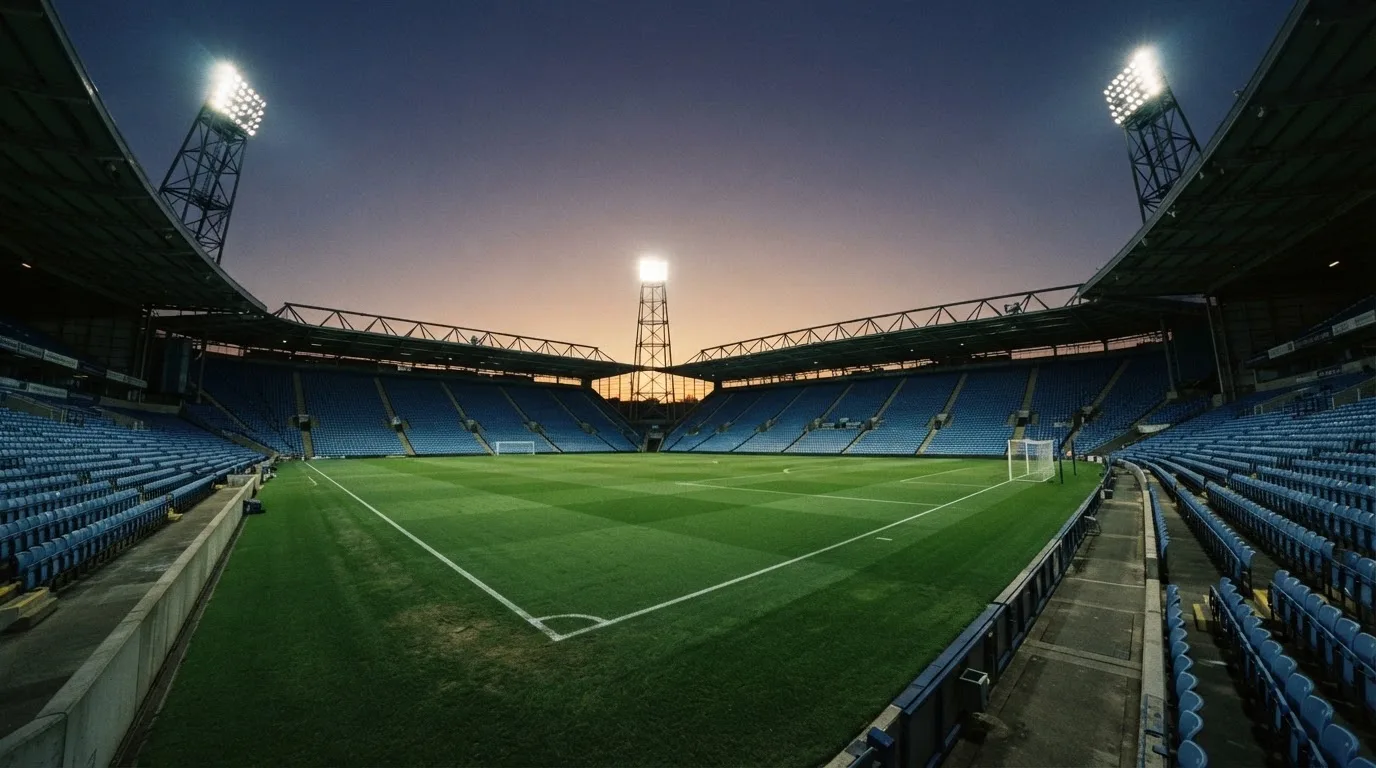 An empty football stadium with floodlight masts at dusk