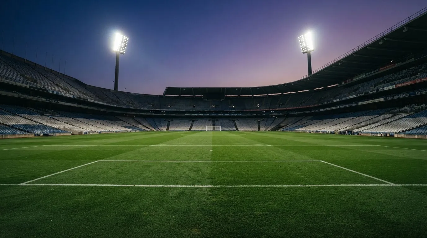 An empty football stadium with floodlight masts at dusk
