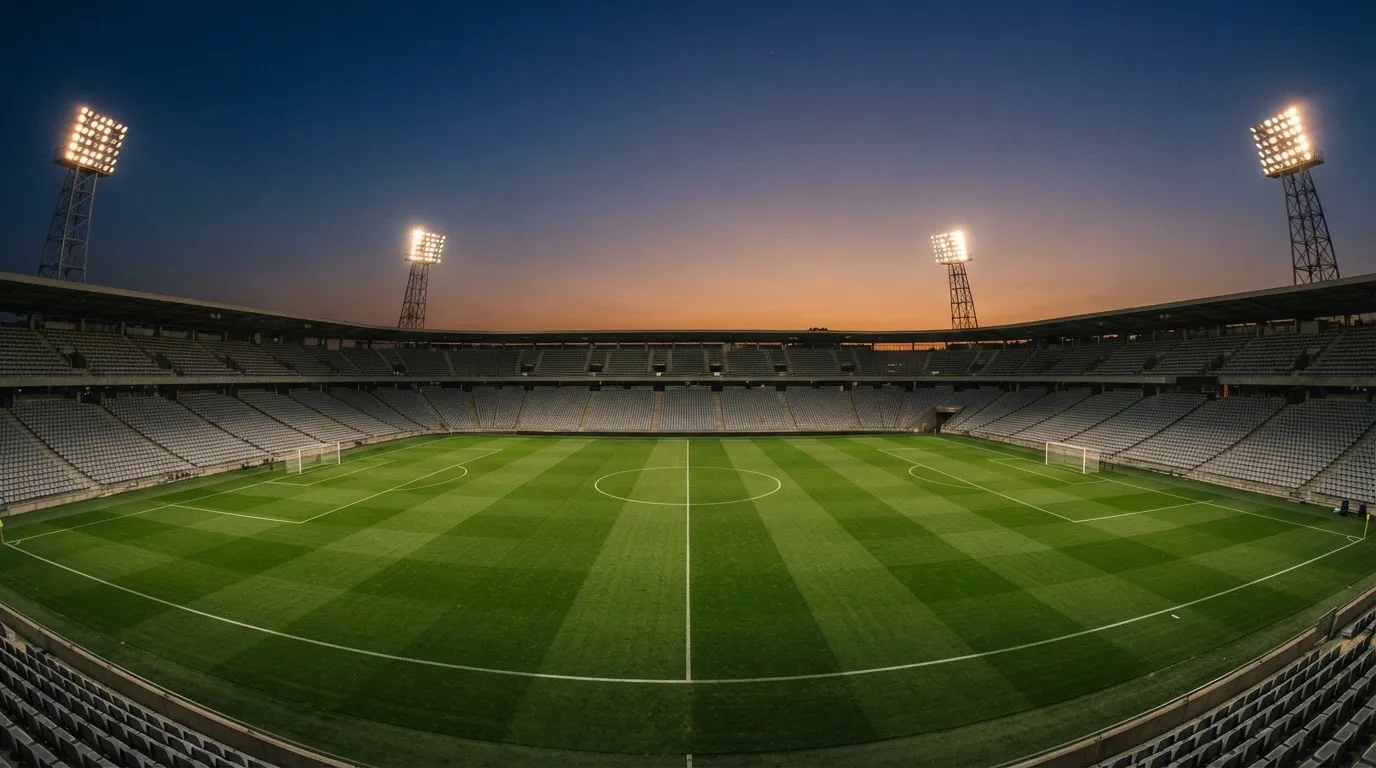 An empty football stadium with floodlight masts at dusk