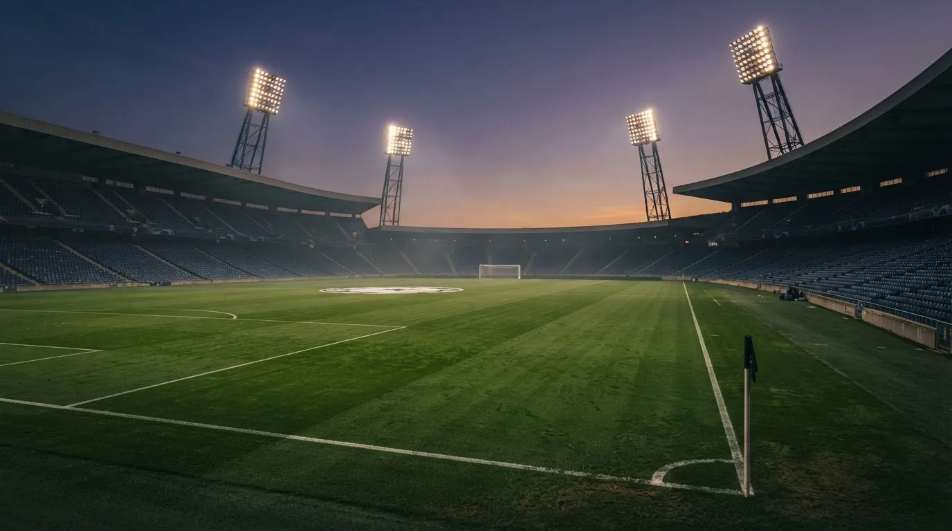 An empty football stadium with floodlight masts at dusk