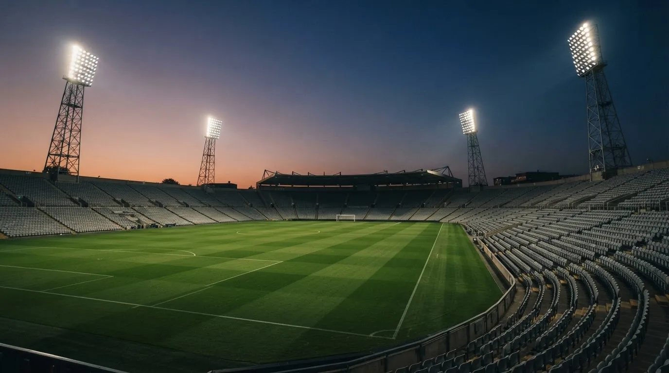 An empty football stadium with floodlight masts at dusk