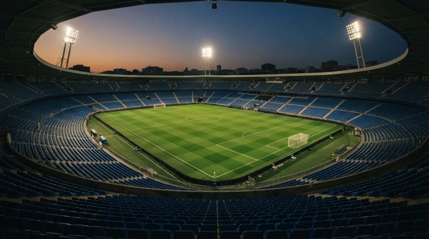 An empty football stadium with floodlight masts at dusk