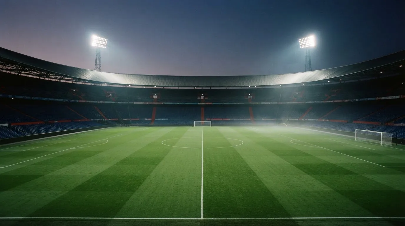 An empty football stadium with floodlight masts at dusk