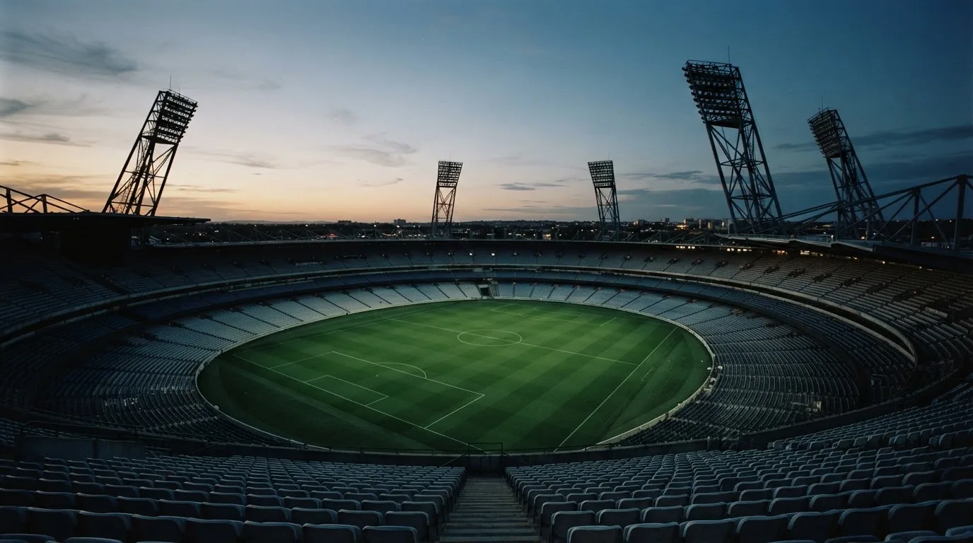 An empty football stadium with floodlight masts at dusk