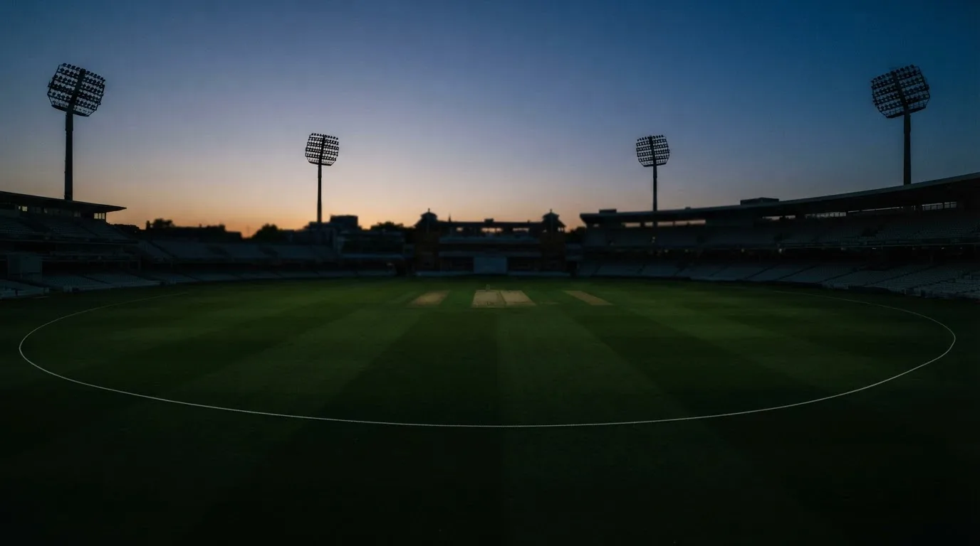 An empty football stadium with floodlight masts at dusk