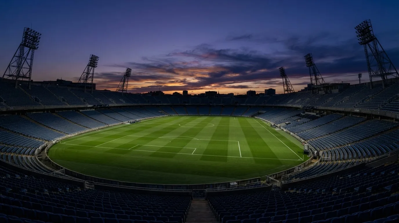 An empty football stadium with floodlight masts at dusk