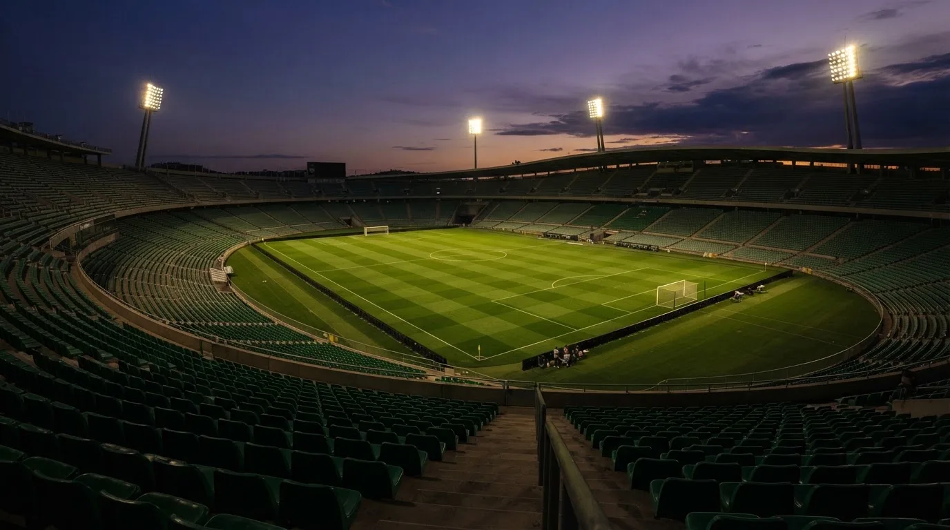 An empty football stadium with floodlight masts at dusk
