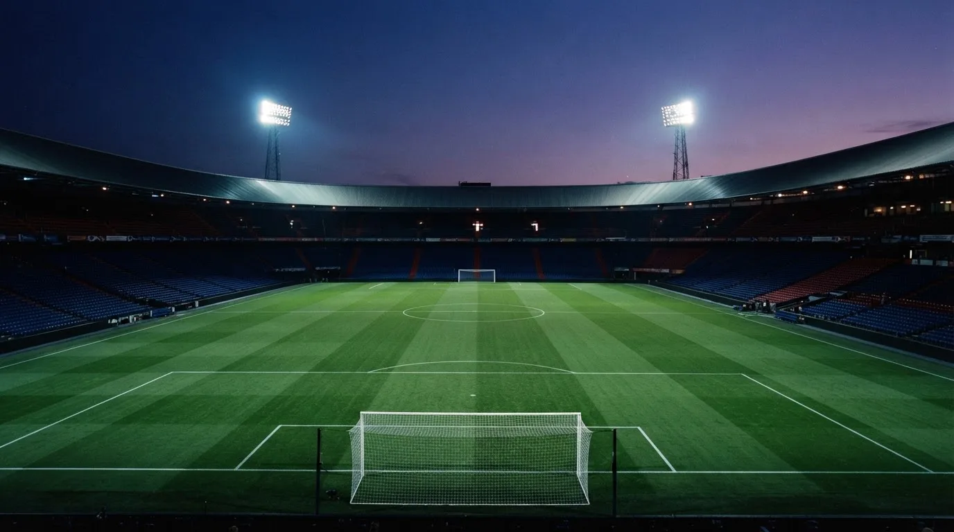 An empty football stadium with floodlight masts at dusk