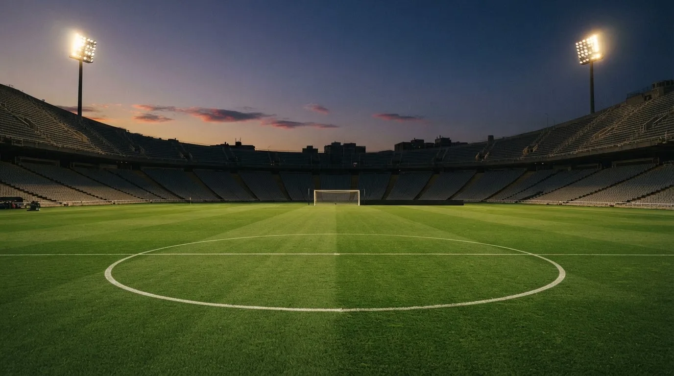 An empty football stadium with floodlight masts at dusk
