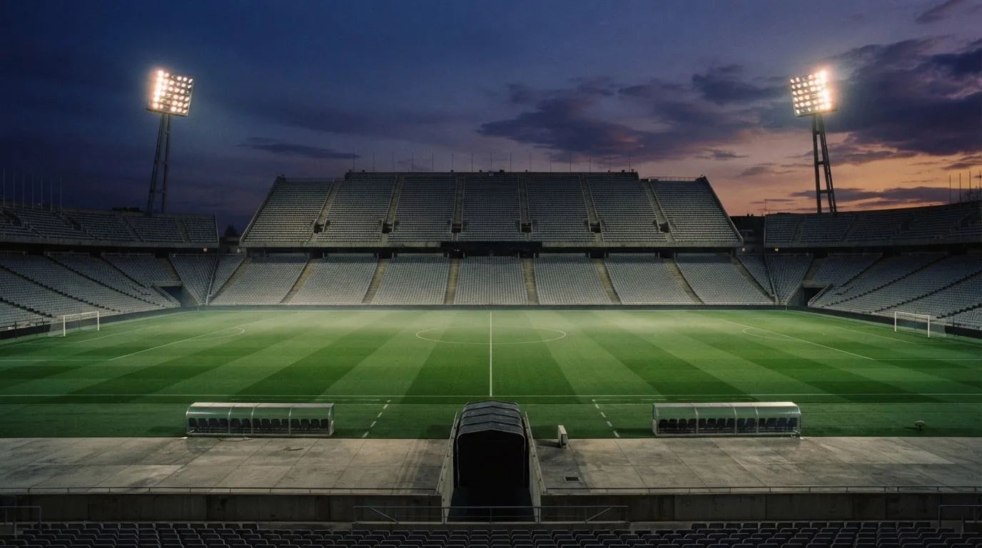 An empty football stadium with floodlight masts at dusk