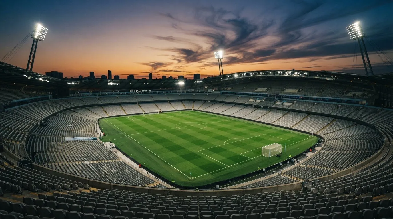 An empty football stadium with floodlight masts at dusk