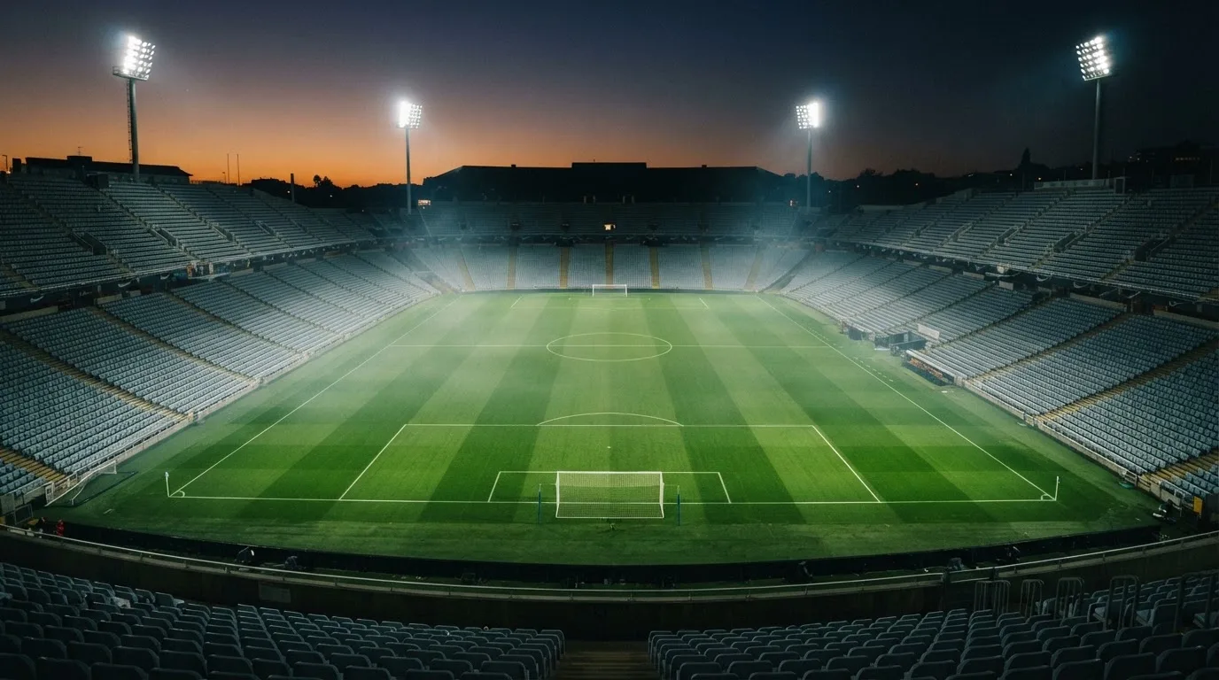 An empty football stadium with floodlight masts at dusk