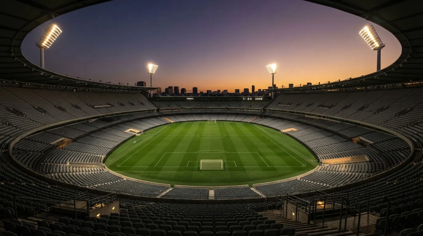 An empty football stadium with floodlight masts at dusk