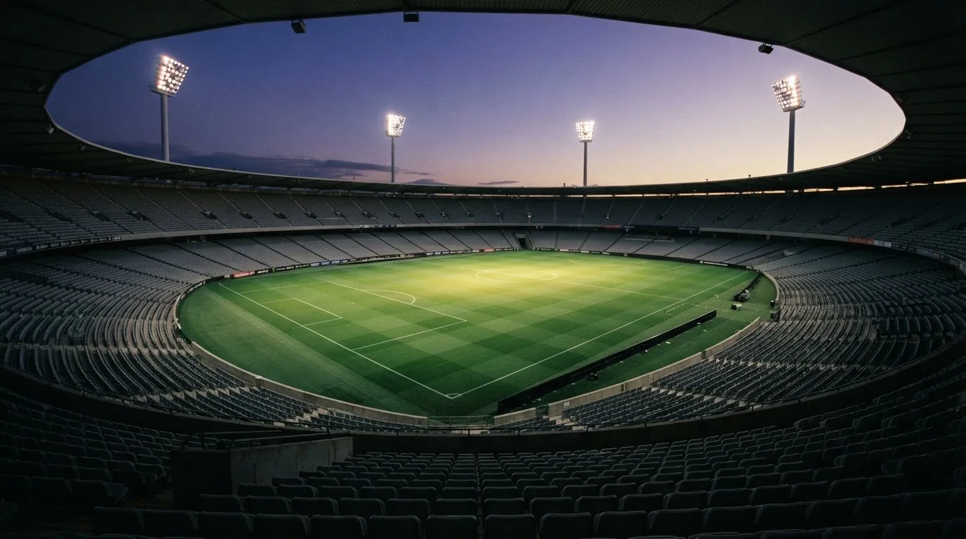An empty football stadium with floodlight masts at dusk