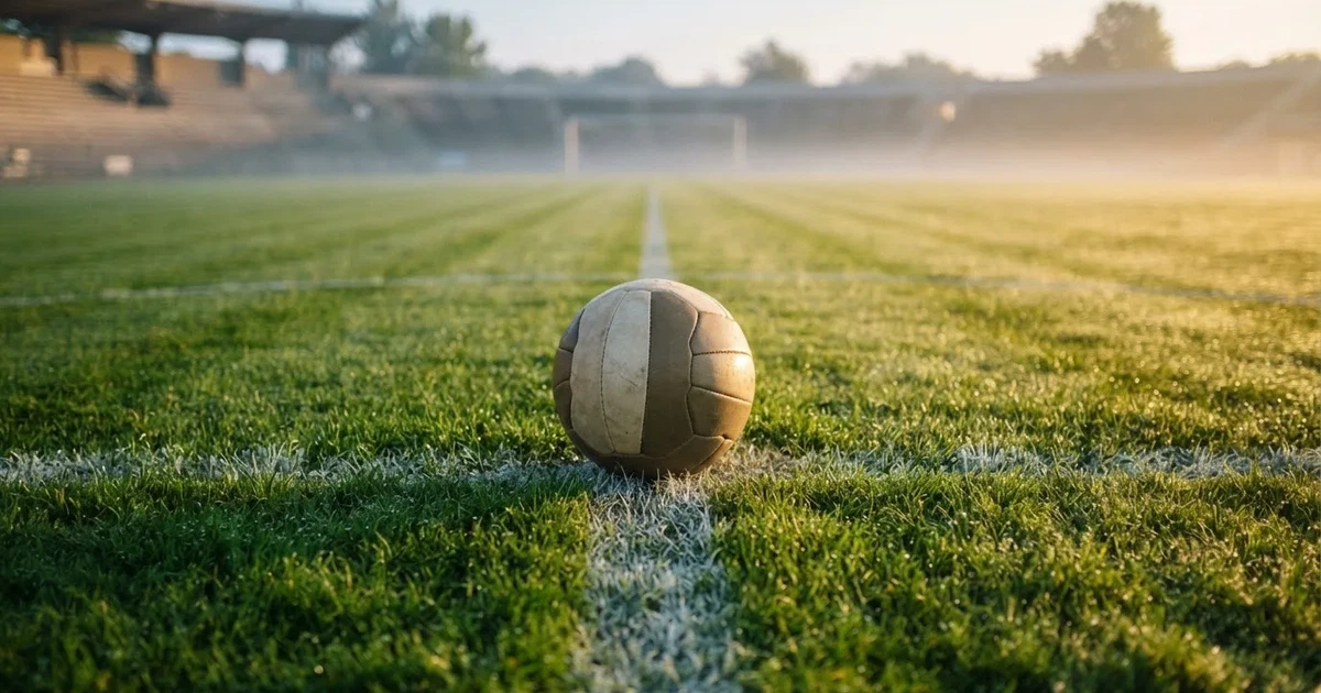A ball on the centre spot of a grass pitch in morning light