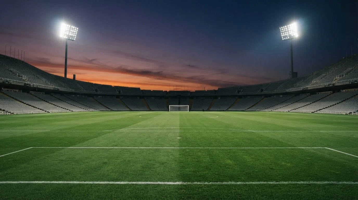 An empty football stadium with floodlight masts at dusk