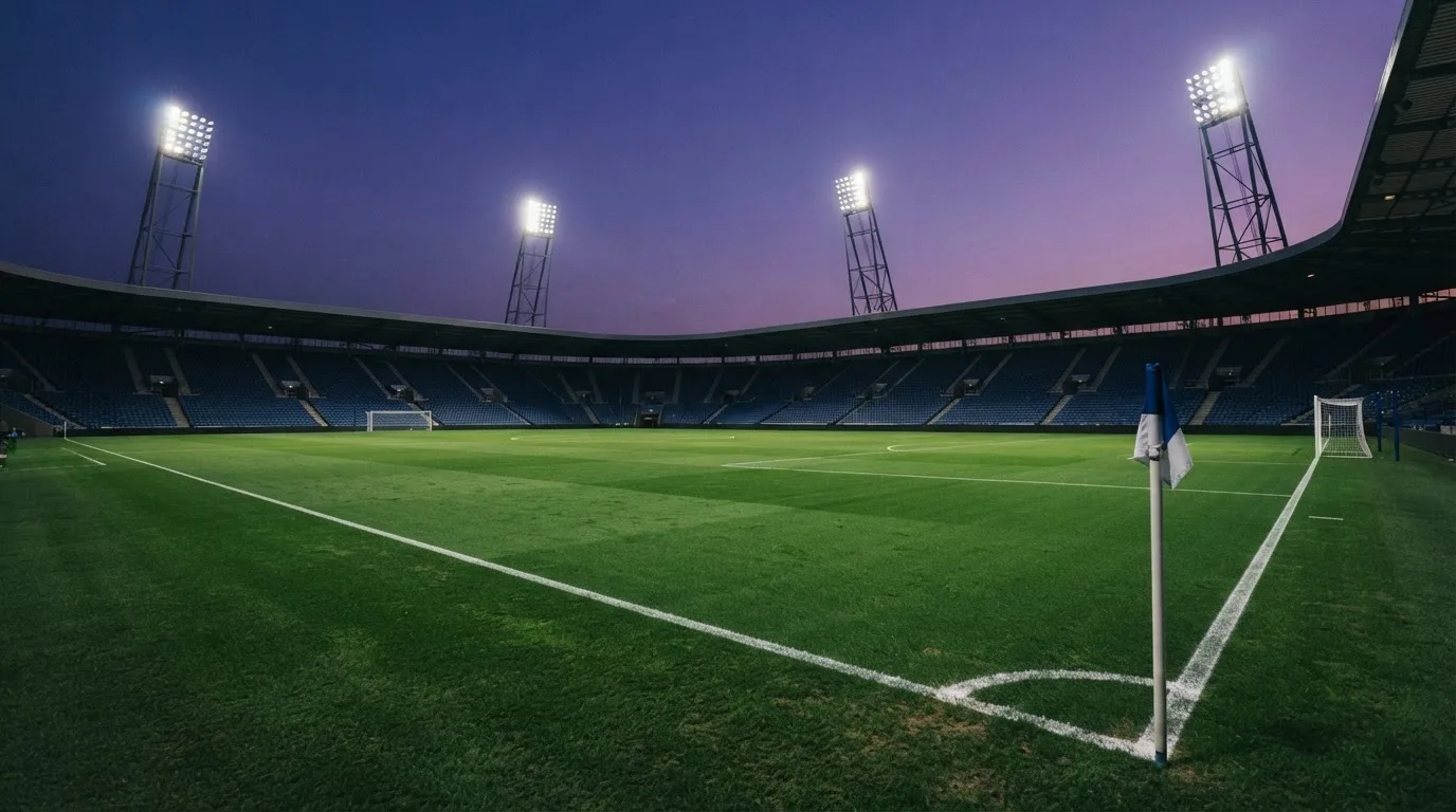 An empty football stadium with floodlight masts at dusk