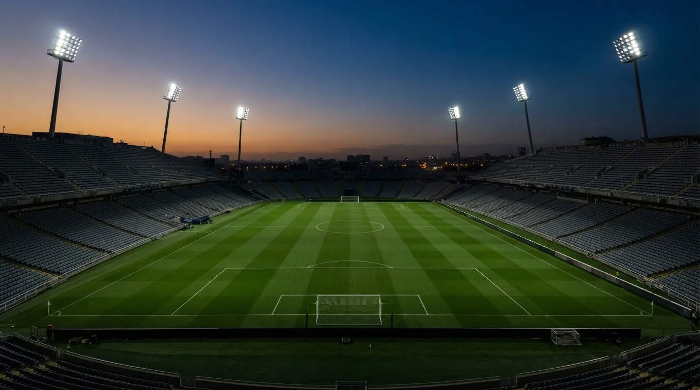 An empty football stadium with floodlight masts at dusk