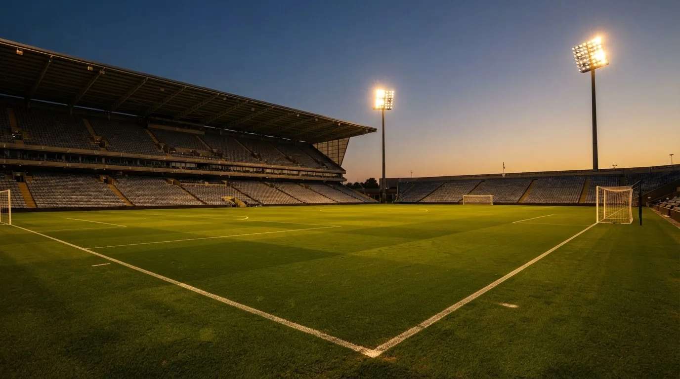 An empty football stadium with floodlight masts at dusk