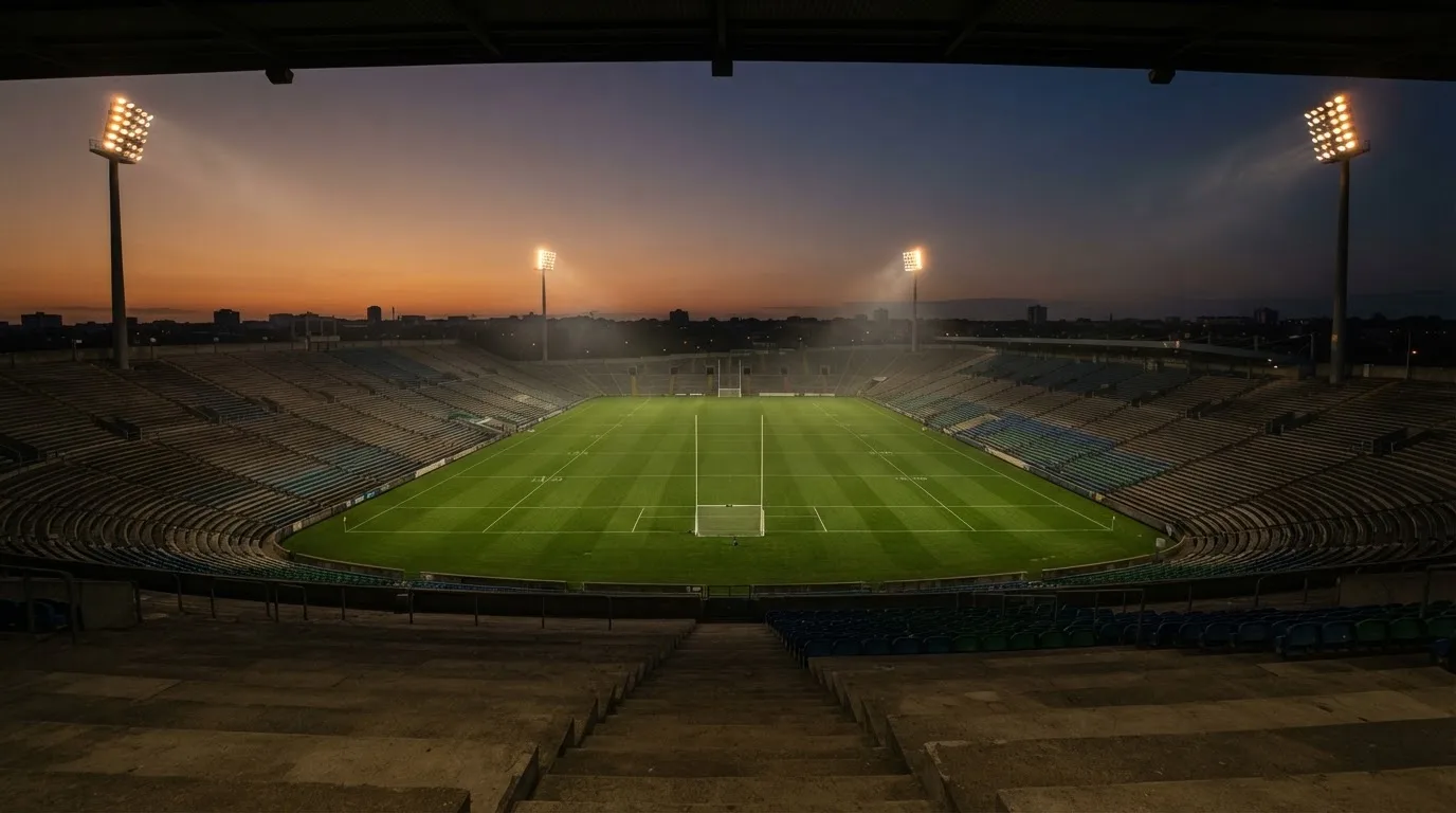 An empty football stadium with floodlight masts at dusk