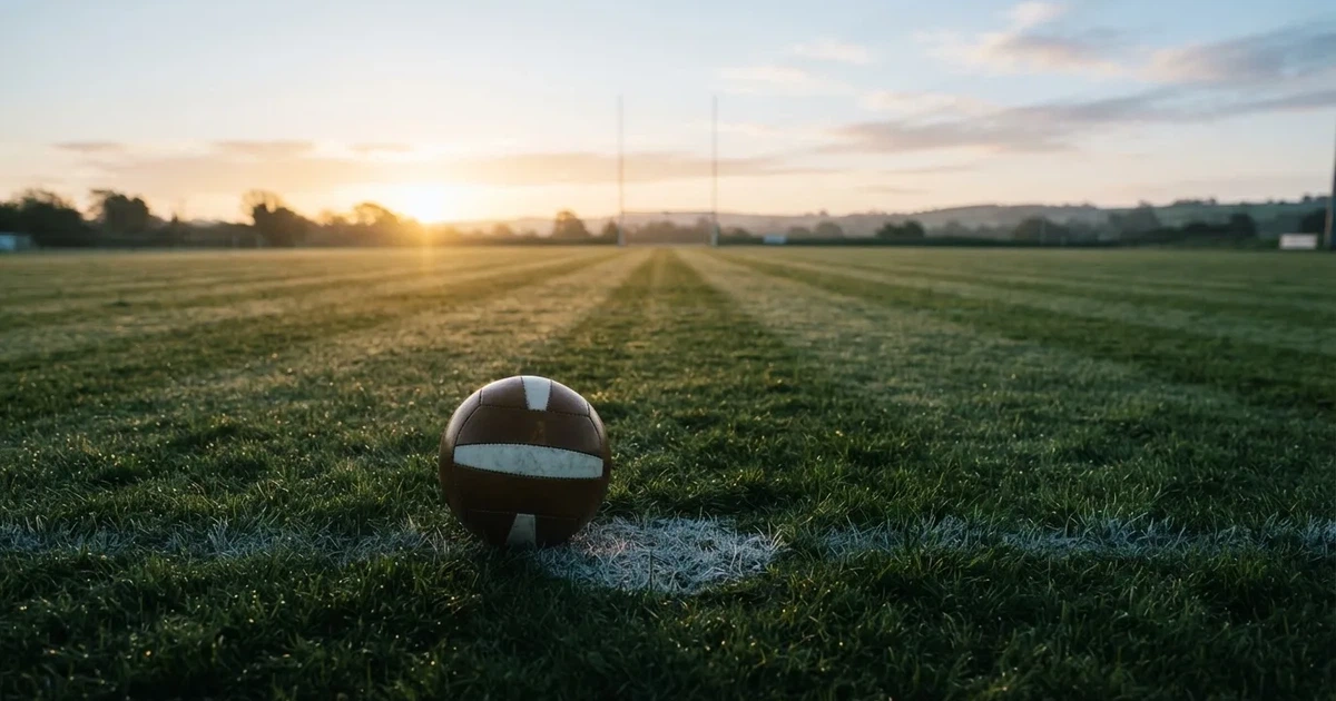A ball on the centre spot of a grass pitch in morning light