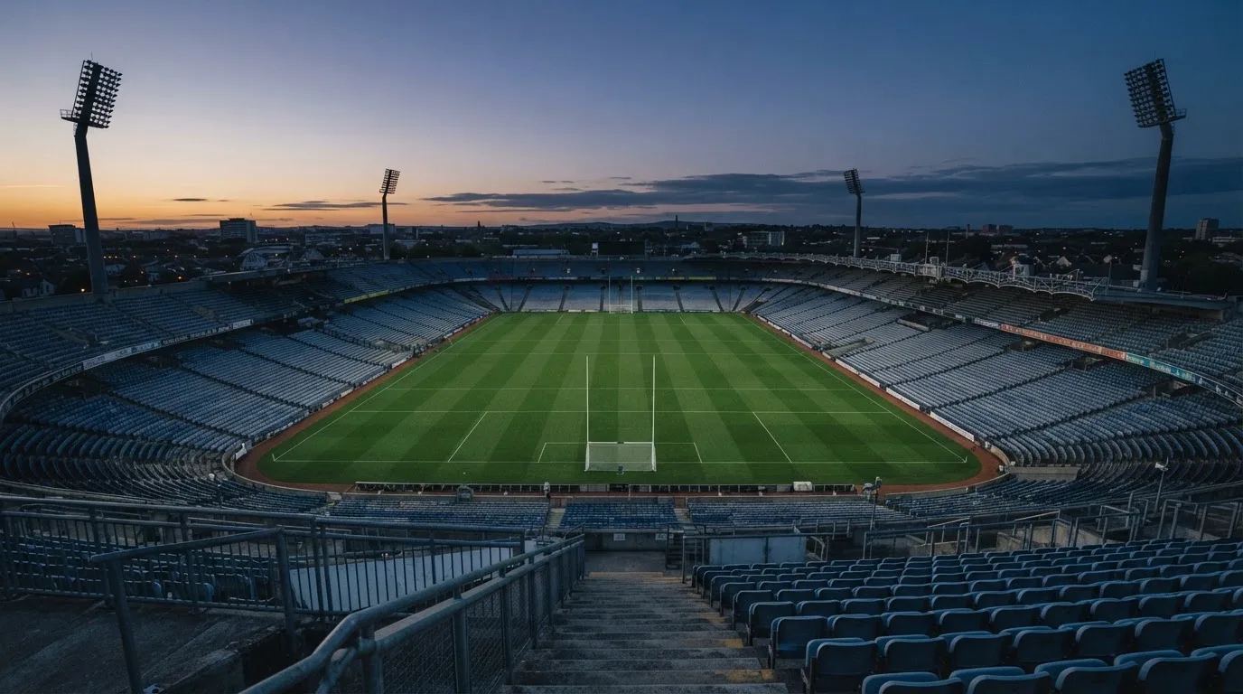 An empty football stadium with floodlight masts at dusk
