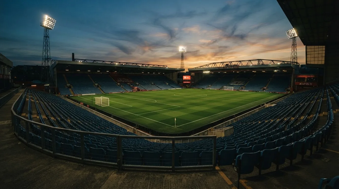 An empty football stadium with floodlight masts at dusk