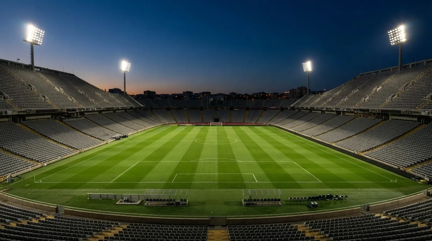 An empty football stadium with floodlight masts at dusk