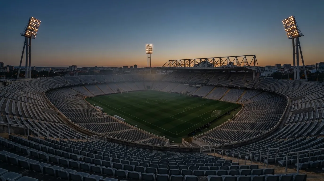 An empty football stadium with floodlight masts at dusk
