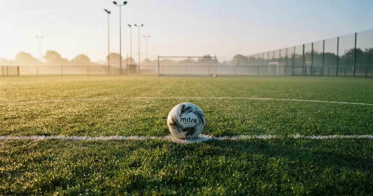A ball on the centre spot of a grass pitch in morning light