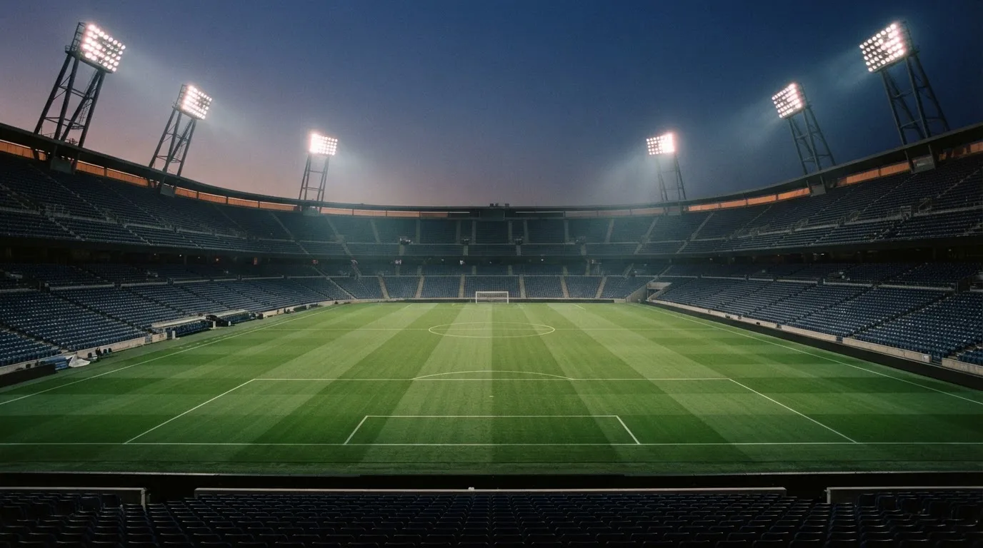 An empty football stadium with floodlight masts at dusk