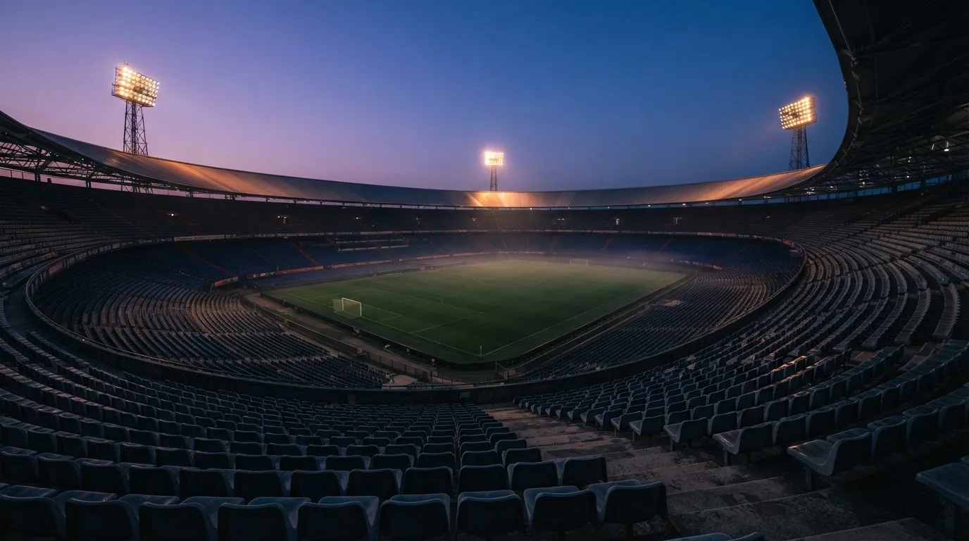 An empty football stadium with floodlight masts at dusk
