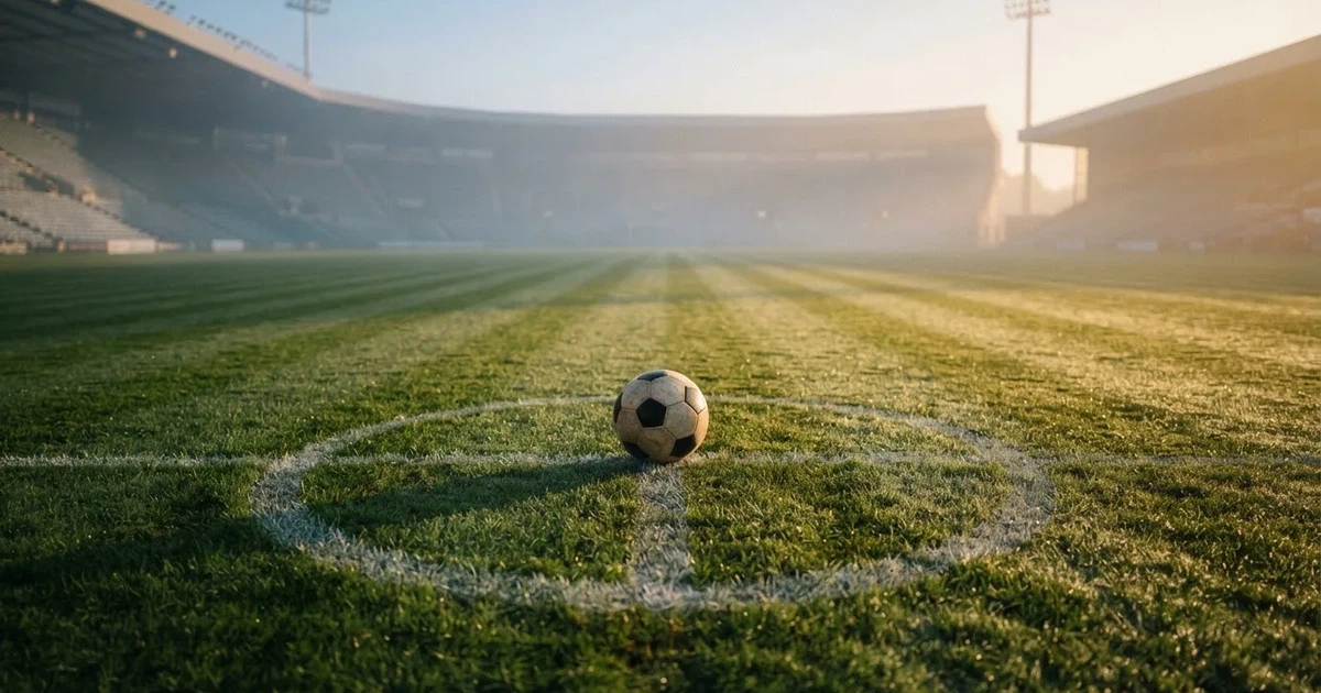 A ball on the centre spot of a grass pitch in morning light